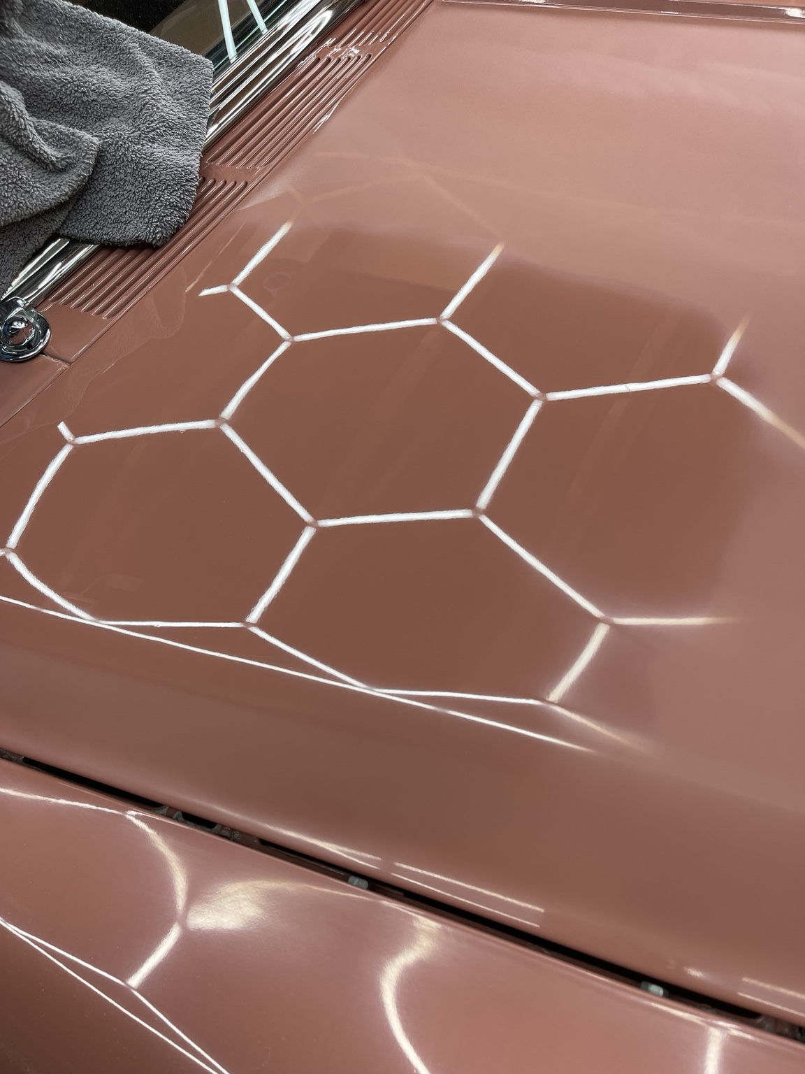 Sanded hood with a polished corner showing crisp overhead light reflections against the surrounding hazy surface